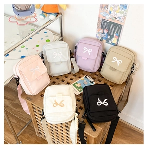 Close-up of cute crossbody bags in six colors with bow decor on a wooden stand