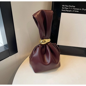 Detail view of burgundy drawstring bucket bag with gold pebble-shaped metal buckle