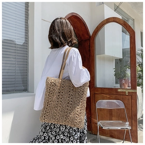 Detailed view of handmade woven hollow pattern and brown leather straps on the tote bag