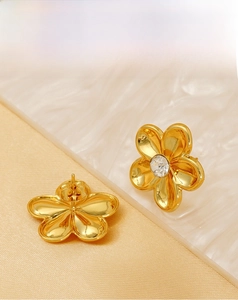 Detailed view of gold flower stud earrings with central crystal and secure butterfly backs