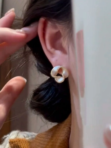 Detail of 14K gold plated clover flower earring featuring a white pearl inlay on model