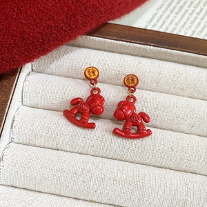 Detailed shot of red rocking horse earrings with pearls and Chinese character fa