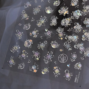 Macro shot of holographic snowflake and bubble nail stickers on silk background