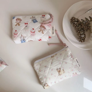 Detailed close-up of quilted floral and animal pattern mini pouches with pink zipper pulls
