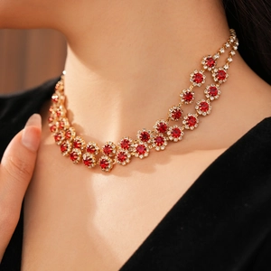 Detail of elegant gold double-layer necklace with red round gemstones on female model