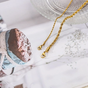Detail of 18k gold plated stainless steel rope chain with a lobster clasp on glass