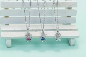 Detailed view of silver boy and girl pendants with pink, blue, and white zircon stones