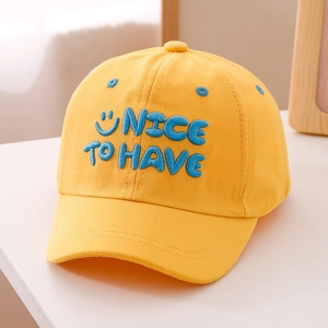 Close-up of bright yellow cotton baseball cap with blue 3D embroidery and happy face