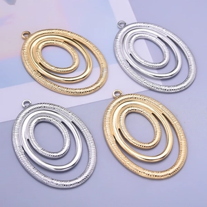 Close-up of irregular textured oval pendant charms in gold and silver finish
