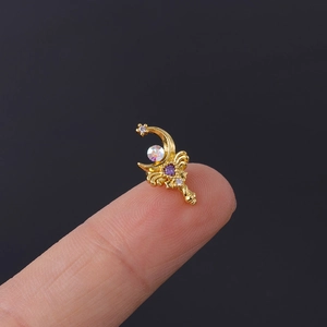 Detailed close-up showing miniature gold crescent moon and star stud earrings on a fingertip