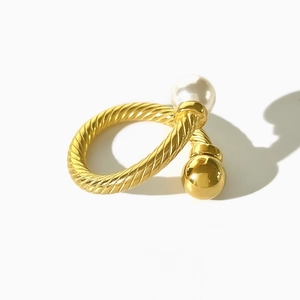 Close-up of twisted 18K gold band ring with white pearl and polished metal bead