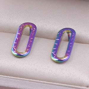 Macro shot of iridescent rainbow stainless steel oval hoop earrings with textured grooves