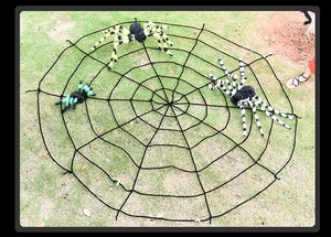 Giant black spider web with three colorful plush spiders displayed on green grass