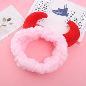 Gros plan d'un bandeau en peluche rose avec cornes de diable et texture douce