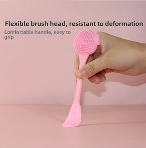 Close-up of dual-ended pink silicone brush for facial cleansing and mud mask application