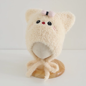 Detail of plush beige cat-ear hat featuring pink bow accents and warm fleece texture