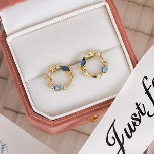Macro shot of celestial star and moon earrings with blue crystals in a pink velvet box