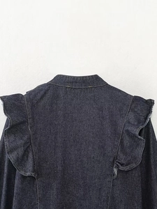 Detailed view of ruffle design and denim texture on back of dark blue denim top