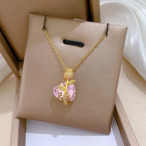 Detailed view of pink heart pendant with golden rose and crystals on silk fabric