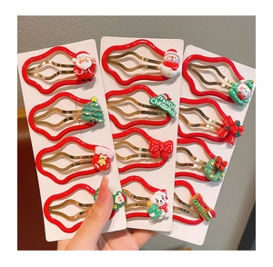 Hand holding a set of Christmas hair clips with Santa, snowman, and tree motifs on white card