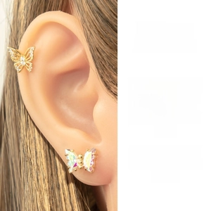 Detailed close-up of butterfly ear cuff and rainbow stud on ear with warm lighting