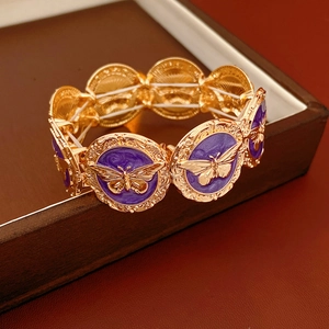 Detail of vintage gold bracelet with purple enamel butterfly charms and ornate motifs