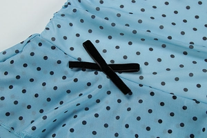 Détail de tissu en résille bleu clair à pois noirs et nœud décoratif en feutrine