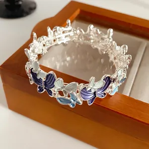 Elegant silver butterfly stretch bracelet with blue enamel gradient on wooden stand