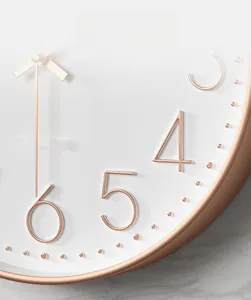 Macro shot of rose gold 3D numbers and quartz movement detail on a white wall clock
