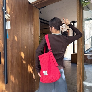 Rear view of a person wearing a large red quilted knit shoulder bag for daily commuting