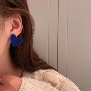 Close-up of model wearing large royal blue velvet heart earrings with matte finish