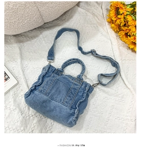 Flat lay of a vintage blue denim handbag with shoulder strap on a white fabric surface