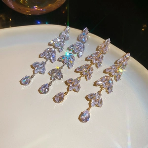 Macro shot of sparkling silver leaf tassel earrings with marquise zircons on white porcelain