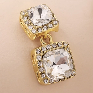 Detailed macro view of gold square stud earrings with clear crystal inlay and micro-pavé