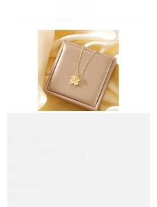 Detail showing the 18K gold plated clover heart pendant on a thin stainless steel chain