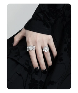 Detail of silver flower rings with pearls worn on hand, showing elegant metal shine