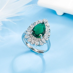 Teardrop emerald ring with halo crystals on a white feather background for women