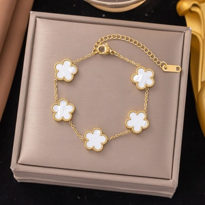 Detail of gold titanium steel bracelet with white five-petal flower charms and lobster clasp