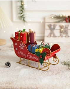 Close-up of red metal Christmas sleigh with gift boxes and Merry Christmas lettering