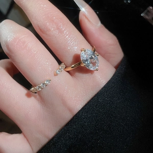 Close-up of golden oval zircon ring and thin micro-paved band on fingers