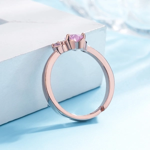 Detail of rose gold and silver ring featuring a heart-shaped pink gemstone setting