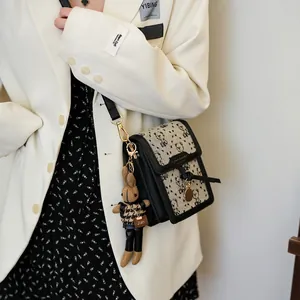 Crossbody phone bag with black and white plaid pattern and cute rabbit charm accessory