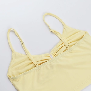 Detail of adjustable metal buckles on light yellow camisole straps and knitted neckline