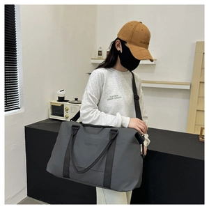 Detailed view of grey Oxford fabric travel bag with adjustable straps and logo embossing