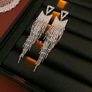 Detailed view of silver triangle tassel earrings with sparkling crystals on black display