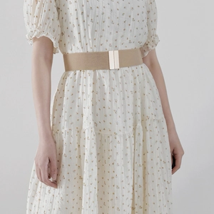 Close-up of beige elastic waist belt with gold metal buckle on floral dress