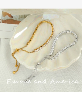 Detail of gold and silver adjustable tennis bracelets with square zircons on shell tray