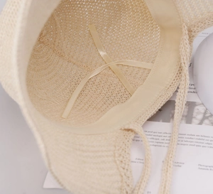 Detailed interior of beige woven straw sun hat featuring adjustable ribbon and sweatband