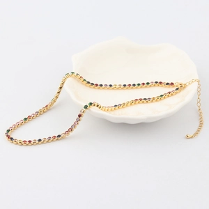 Detail of gold-plated rainbow tennis necklace with colorful zircon stones in a shell dish