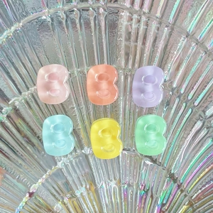 Close-up of colorful jelly resin B-letter charms on a textured glass plate decoration